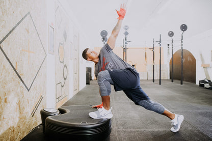 Man in a lunge with his front foot on the Power Plate pro5HP, reaching one arm up