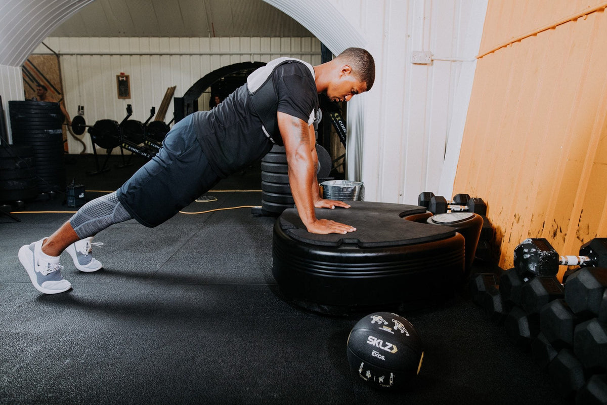 Man doing a push up with his hands on the Power Plate pro5HP platform in a gym