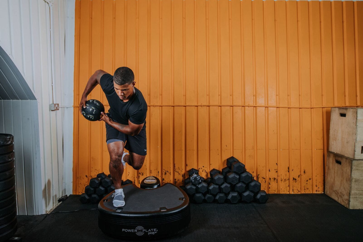 Man balancing on one leg on the Power Plate pro5HP while holding a medicine ball