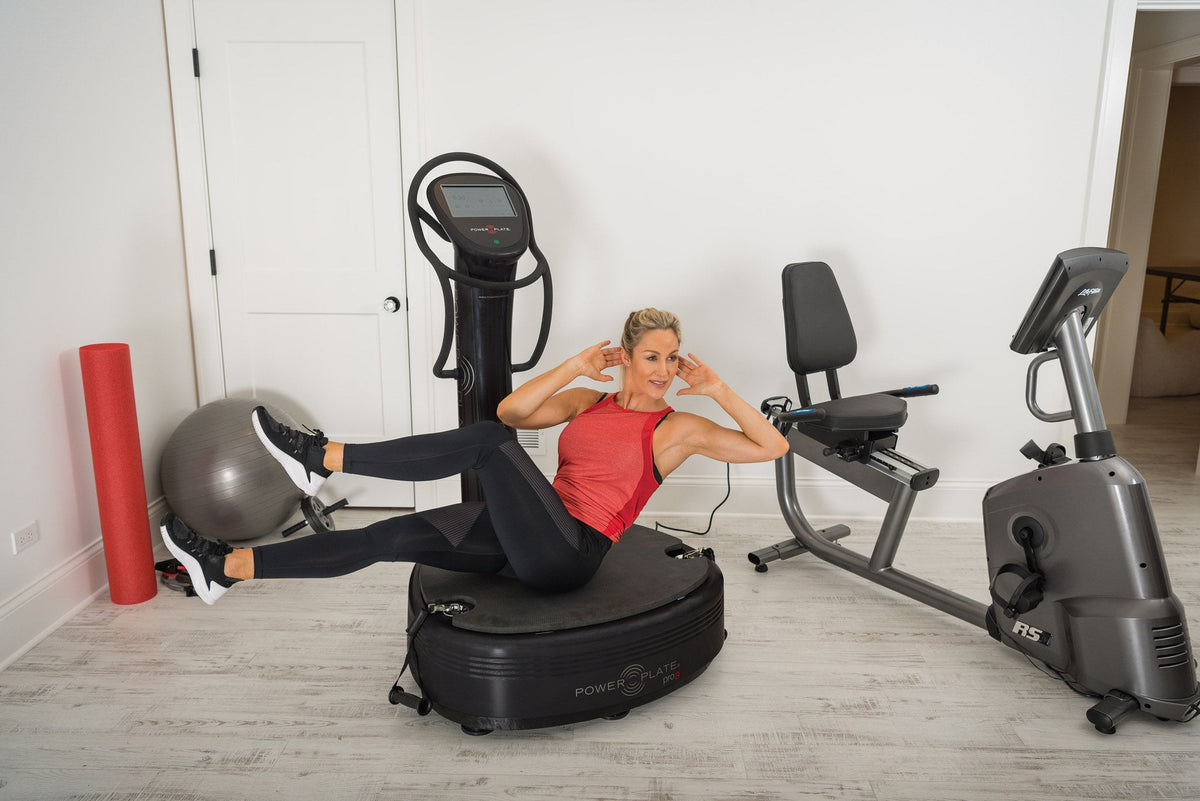 Woman doing a seated core exercise on the Power Plate pro8 platform with her legs raised