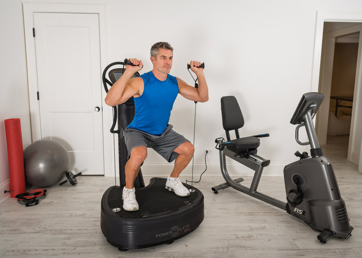 Man holding a squat on the Power Plate pro8 while pulling the proMOTION resistance cables