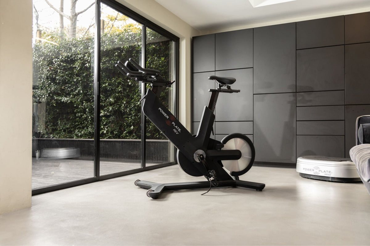 Power Plate REV in matte black in a home gym, seen from across the room