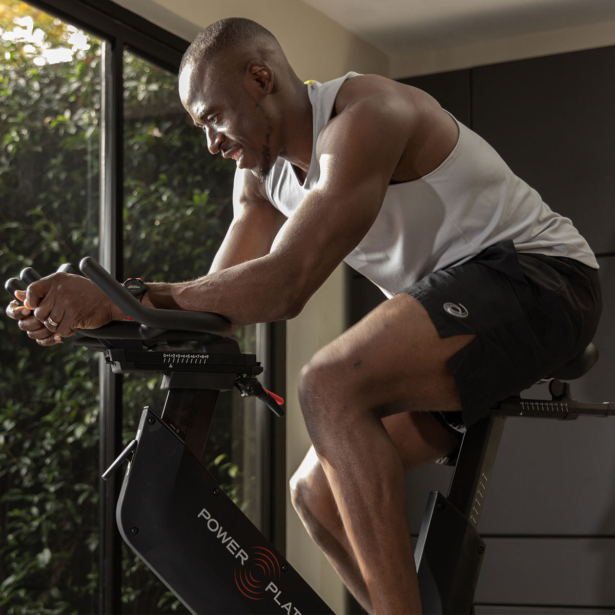 Close view of a man riding the Power Plate REV with his forearms on the handlebars