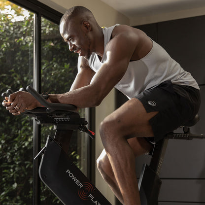 Close view of a man riding the Power Plate REV with his forearms on the handlebars