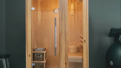 SunRay Aston indoor sauna photo film: glass front, Harvia heater and its knobs, bench with bucket, thermometer and the caged ceiling light