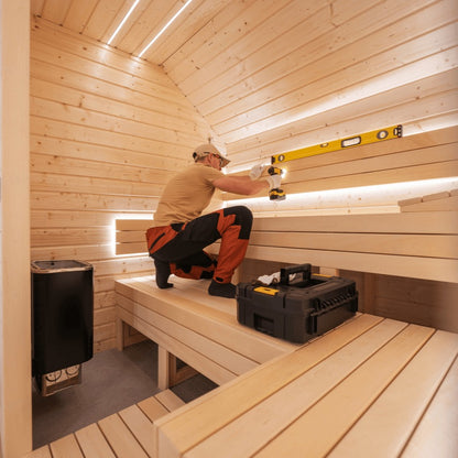 Assembly technician checking level alignment inside a sauna during professional sauna assembly service