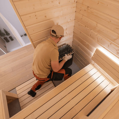 Assembly team technician placing the sauna heater during in-home sauna assembly