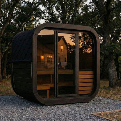SaunaLife CL5G Cube Series 4-Person Outdoor Sauna Kit, black finish, in a garden at dusk
