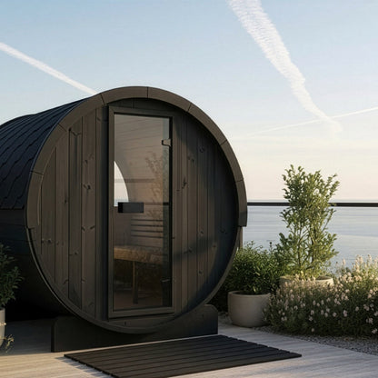 SaunaLife E8W Ergo Series 6-Person Outdoor Barrel Sauna Kit, Rear Window, black finish, on a terrace above the sea