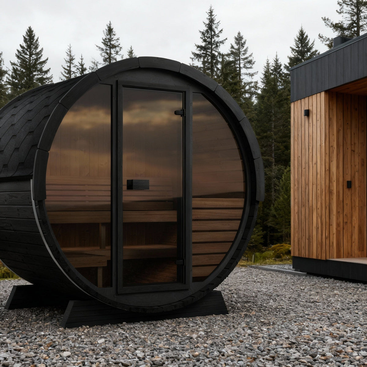 SaunaLife EE6G Ergo Elegance 4-Person Outdoor Barrel Sauna Kit, Glass Front, black finish, on a coastal deck at dusk