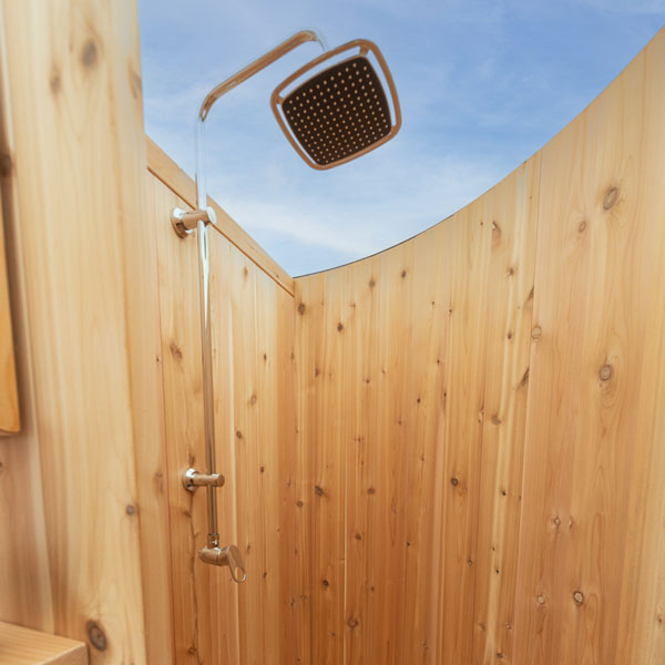 Square rain head on its chrome riser against the vertical cedar staves of the Skylight, open sky above, the hardware is not included.