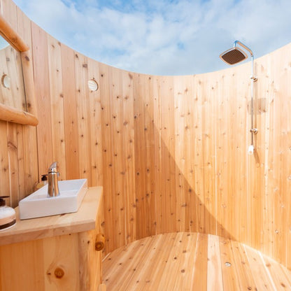 The shower side inside the Skylight: square rain head, riser and hand shower, none included, with the vessel sink at left and sky above.