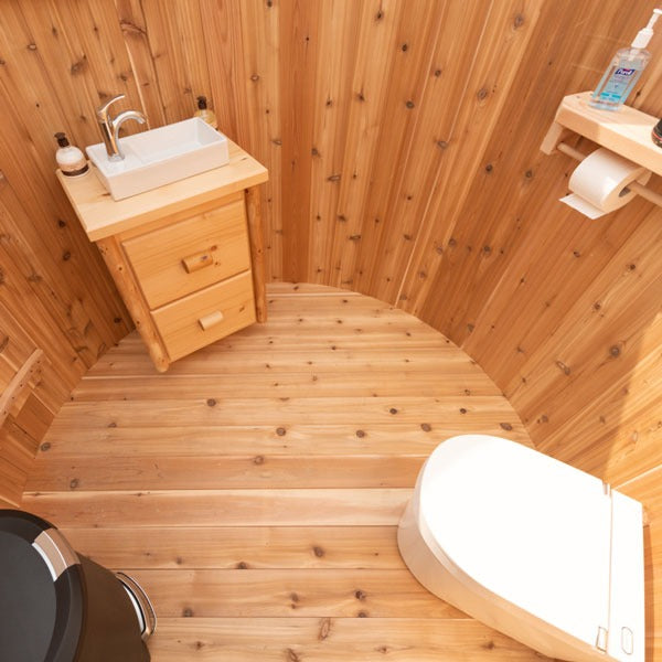 Inside the Skylight from the doorway: the optional vanity and sink, the optional Separett toilet, bottle shelf and paper holder on cedar walls.