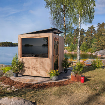 ThermaSol Solaris solar powered sauna cabin beside a lake, with planting and a deck