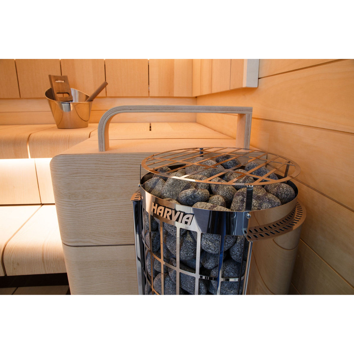 Harvia Cilindro sauna heater with its timber guard, standing beside the sauna bench