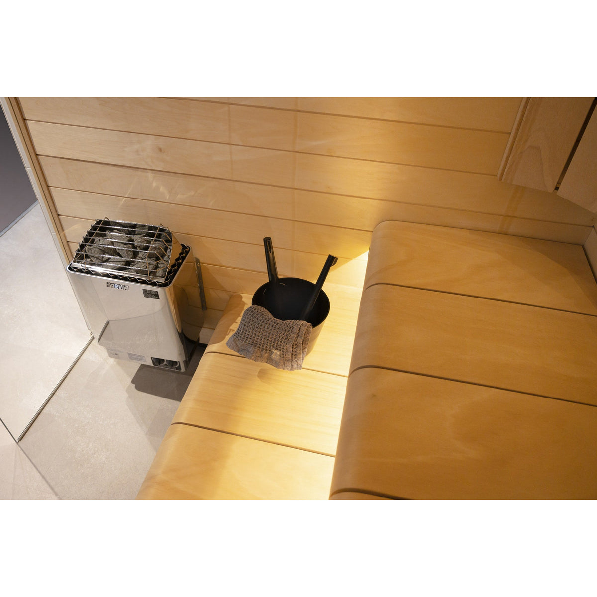 Harvia KIP sauna heater mounted beside timber benching in a home sauna