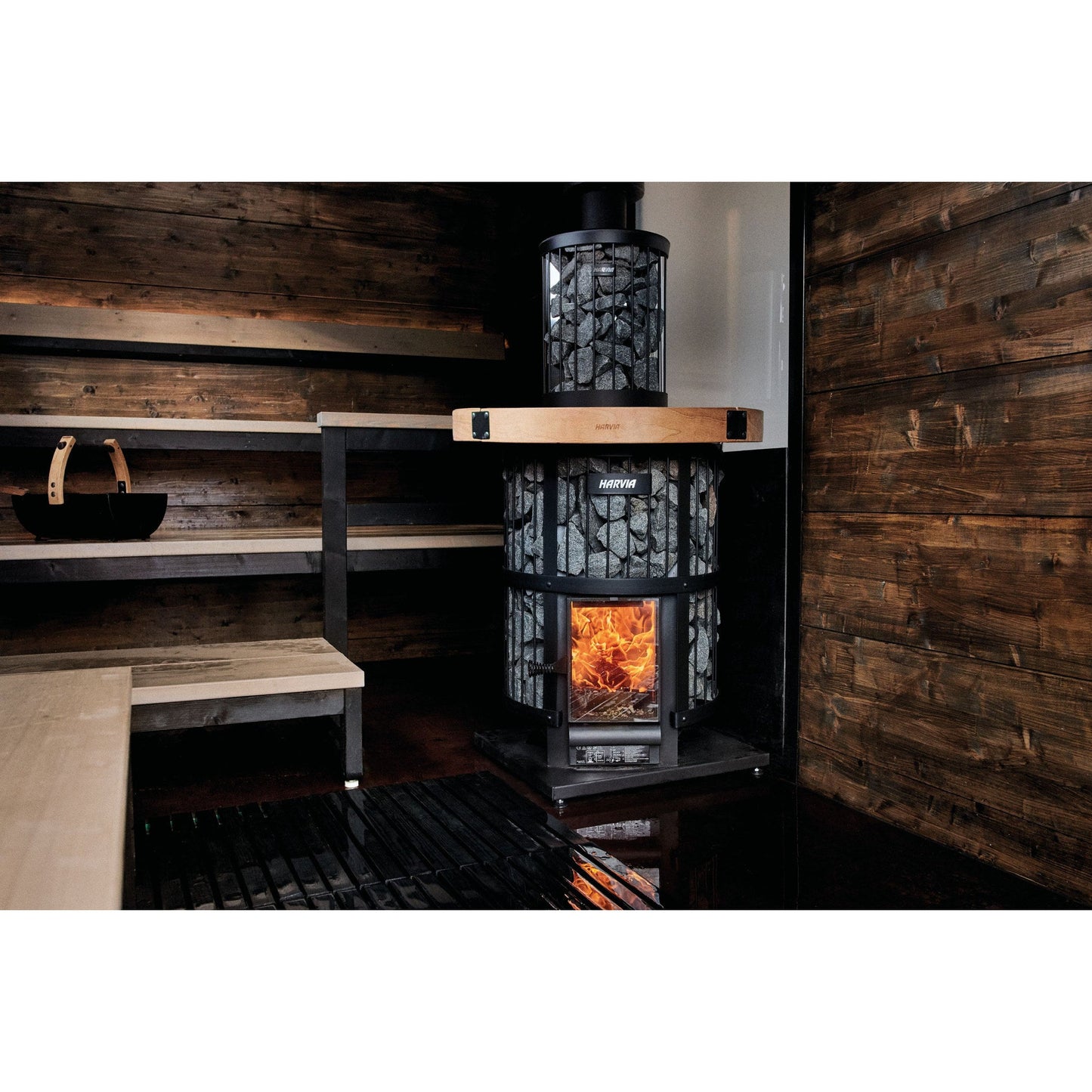 Harvia Legend wood stove burning in a dark timber sauna room
