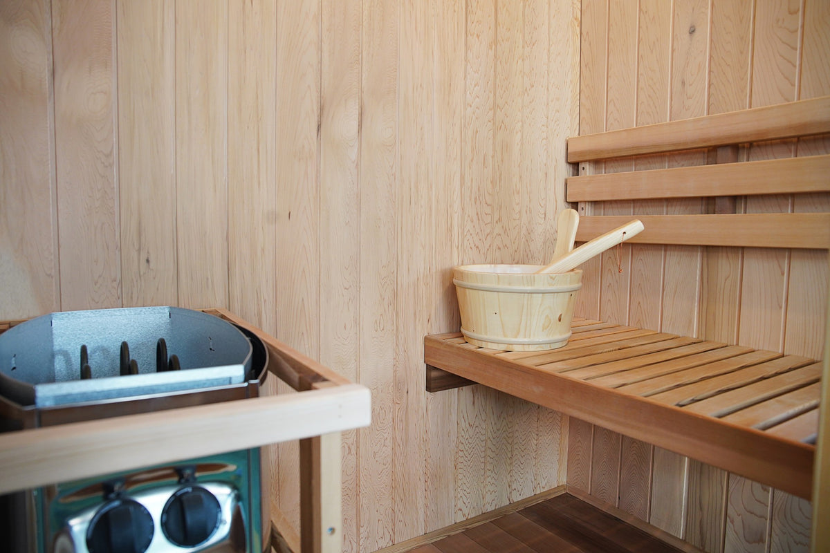 Inside the SunRay Aston: side bench with bucket and ladle, backrest, and the Harvia heater with front control knobs