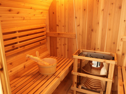 Cedar bench with bucket and ladle beside the heater in its guard rail inside the SunRay Aurora