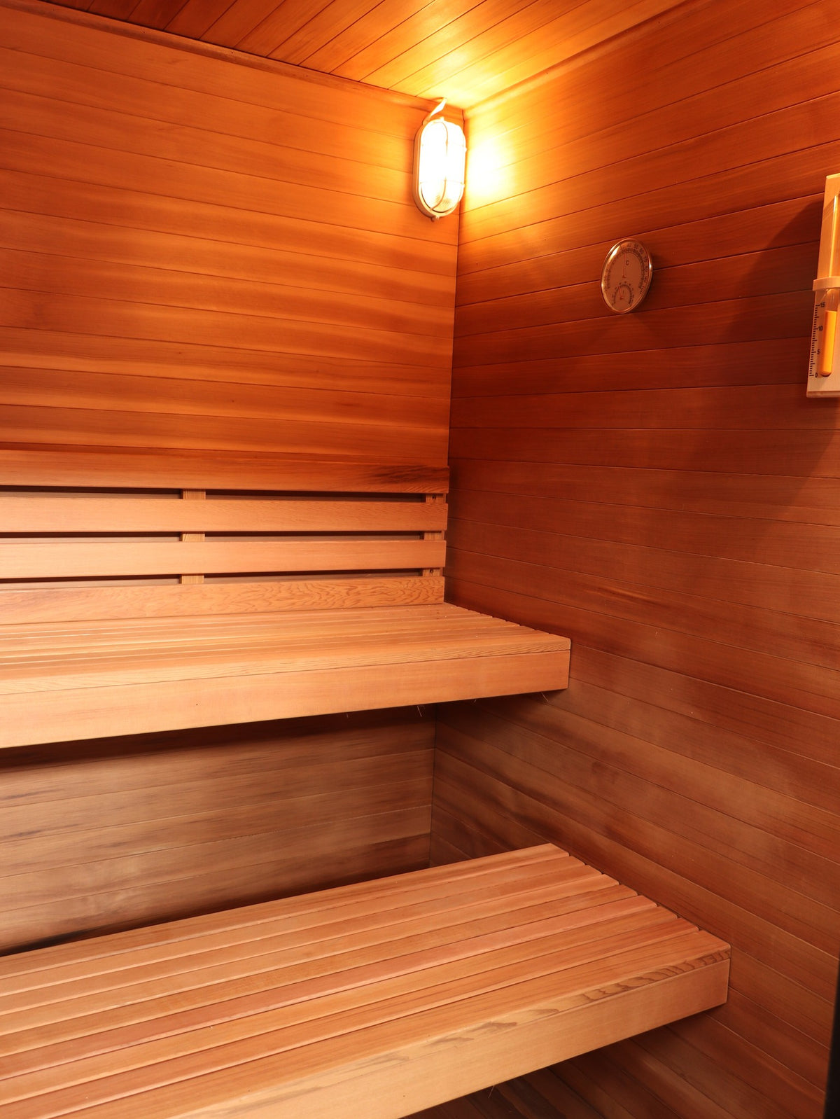 Two-tier benches below the wall light, hygrometer and sand timer inside the SunRay Cayman