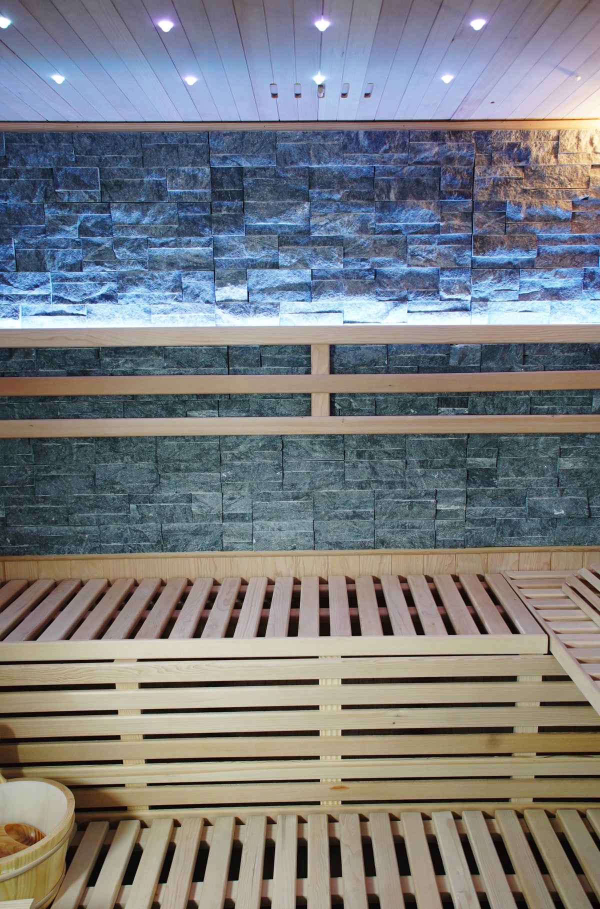 Two-tier benches below the lit stone back wall and ceiling downlights inside the SunRay Galaxie