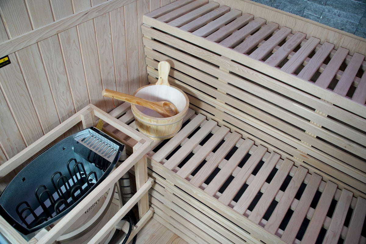 Harvia heater in its wooden guard beside the slatted two-tier benches and bucket inside the SunRay Galaxie