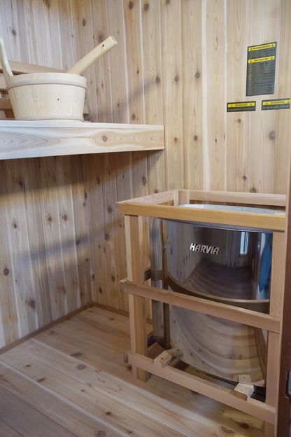 Harvia heater inside its wooden guard rail in a corner of the SunRay Hampton, bucket on the bench above