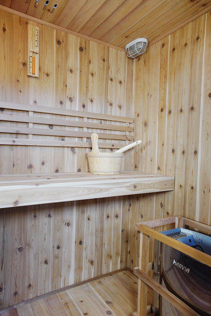 Upper bench with bucket and ladle, backrest and ceiling light inside the SunRay Hampton, Harvia heater in its guard in the corner