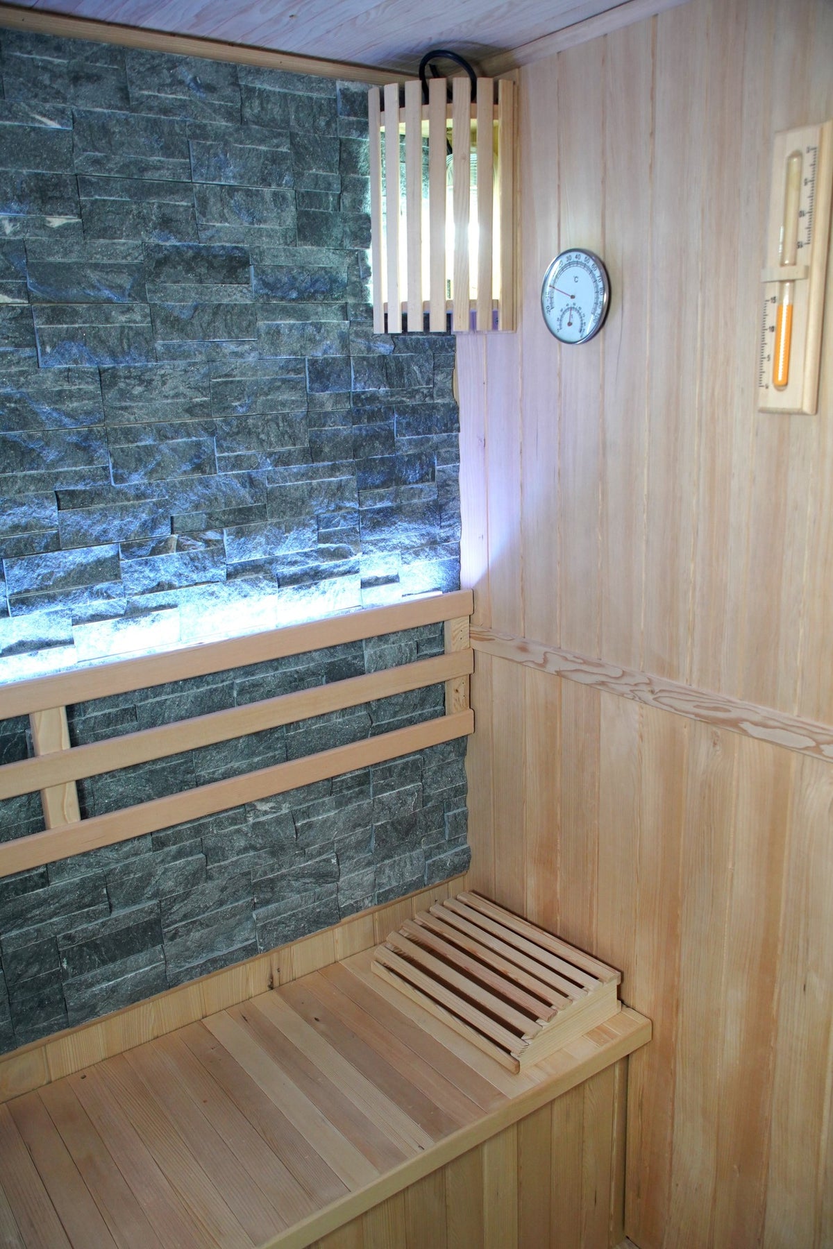 Corner of the SunRay Rockledge: stone wall with backrest, slatted wall light, hygrometer, sand timer and headrest on the bench
