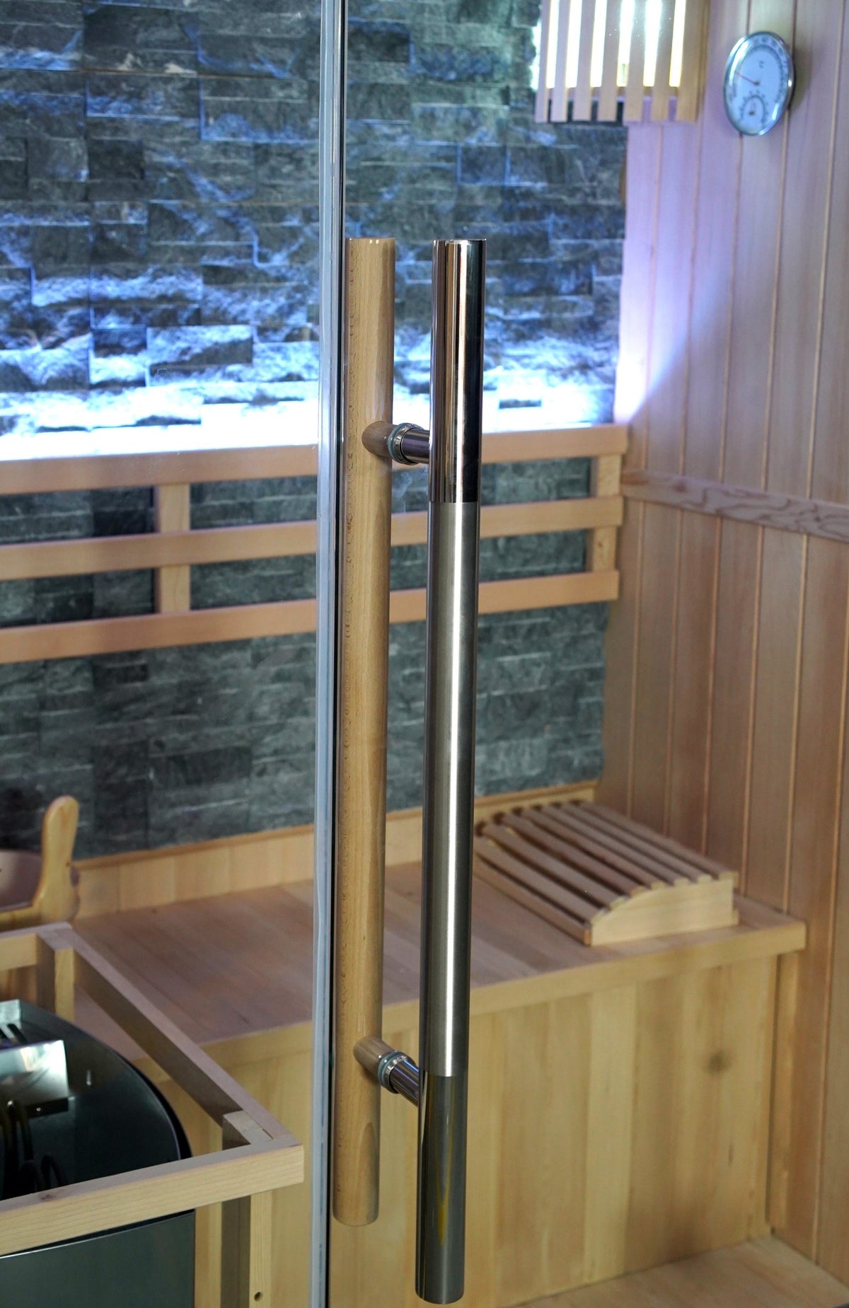 Stainless steel and wooden door handles on the SunRay Rockledge glass door, stone wall and bench behind