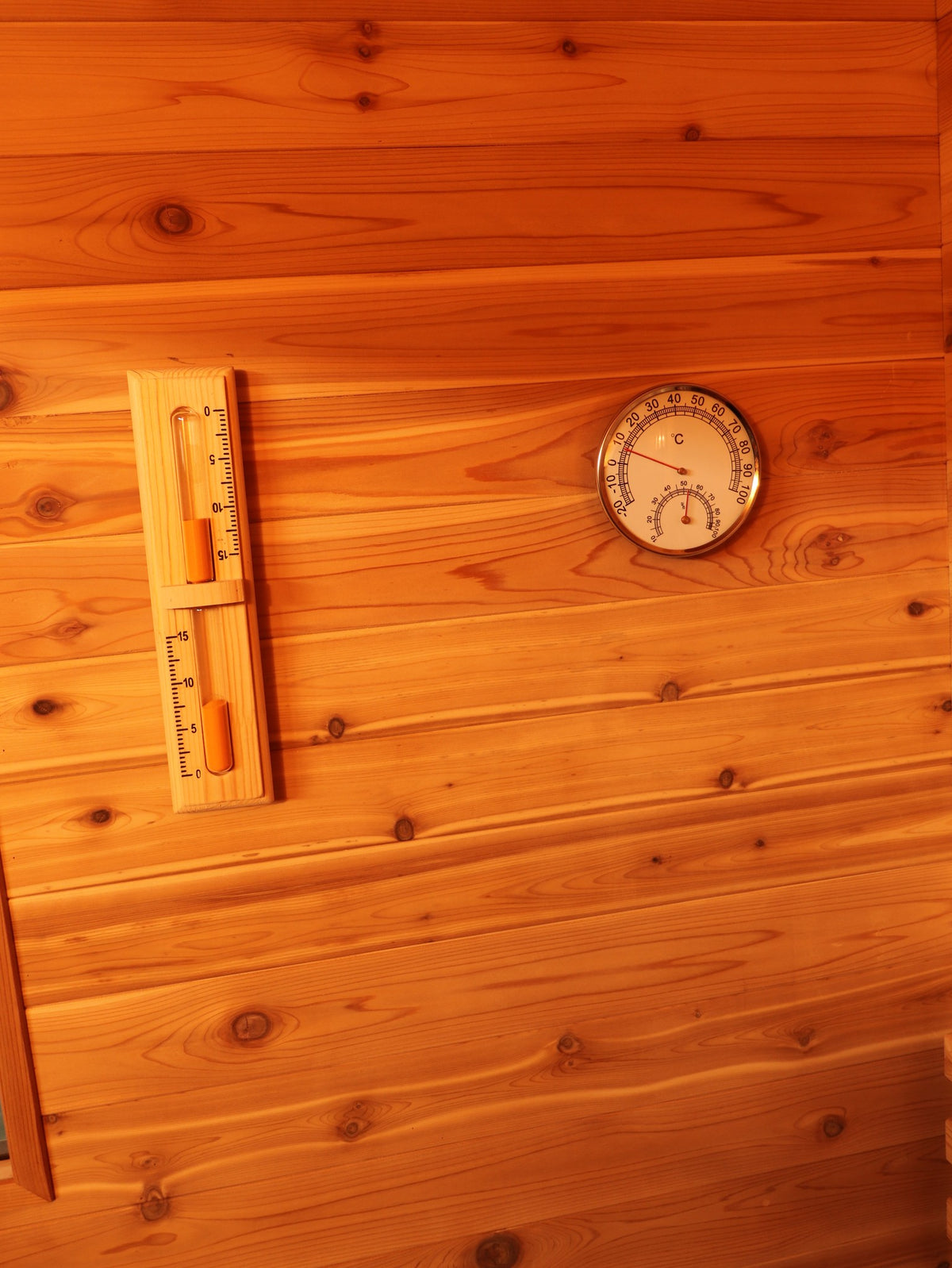 Sand timer and round thermometer and hygrometer dial on the cedar wall inside the SunRay Seneca