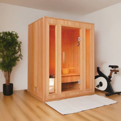 SunRay Southport indoor sauna in hemlock in a light room with a potted tree and an exercise bike: glass door between two narrow glass panels