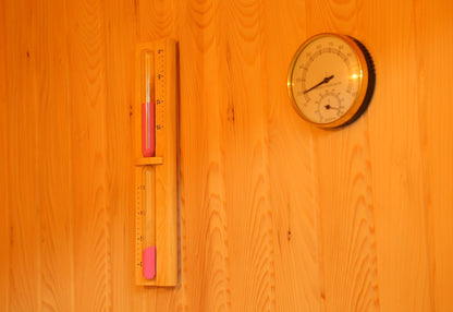 Sand timer and round thermometer and hygrometer dial on the hemlock wall inside the SunRay Southport