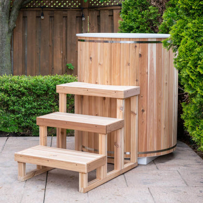 The Baltic Plunge Tub on a backyard patio with cedar steps and cedar lid in place, hedge behind