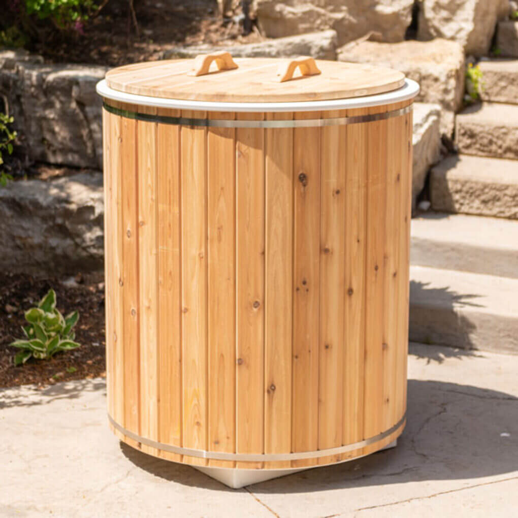 The Baltic Plunge Tub with cedar lid set into a rock garden with boulders