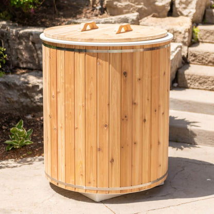 The Baltic Plunge Tub with cedar lid set into a rock garden with boulders