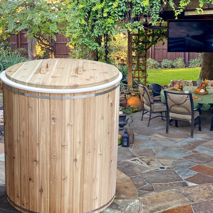 The Baltic Plunge Tub with cedar lid on a flagstone patio beside outdoor dining