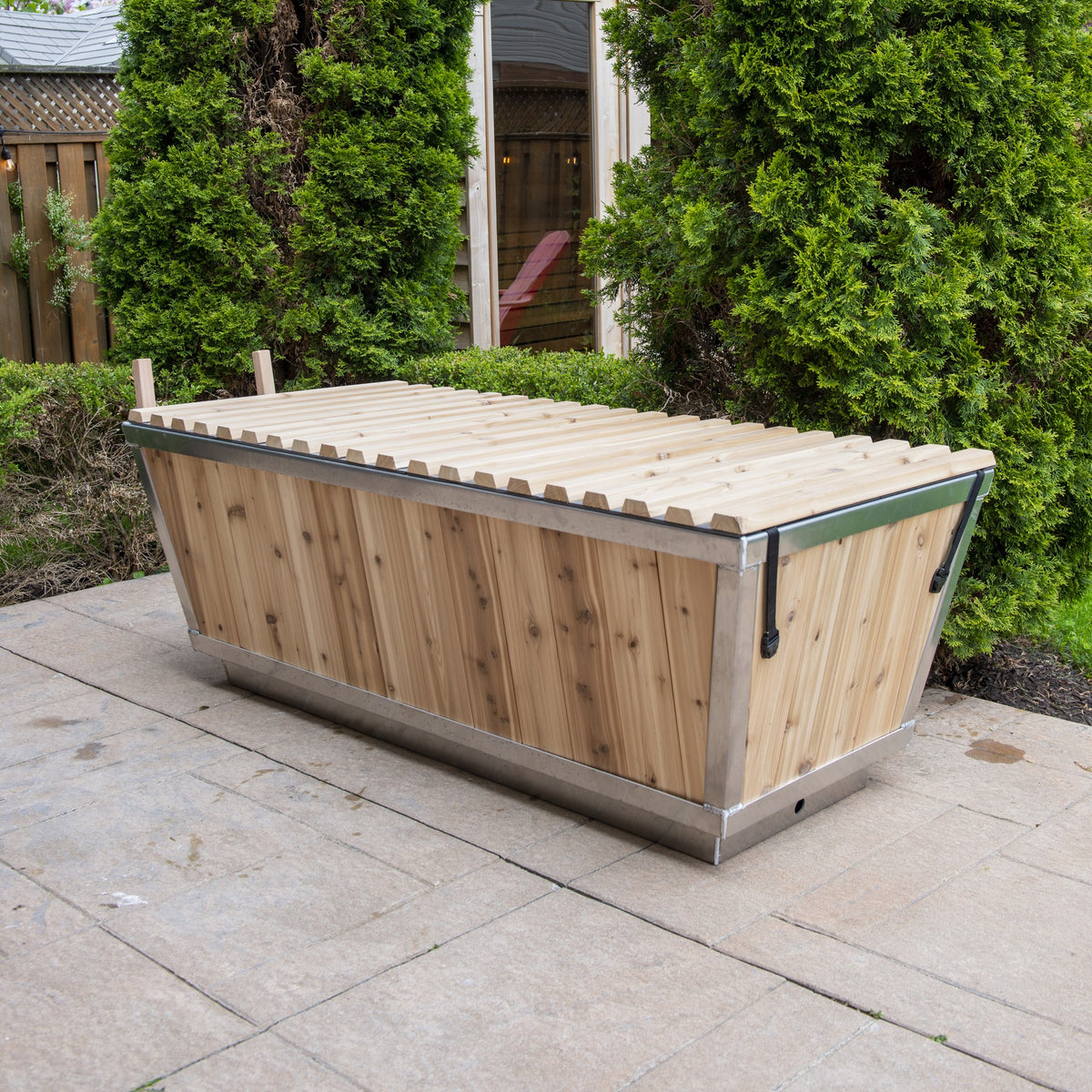 The Polar Plunge Tub by LeisureCraft on a patio with the cedar roll-up cover closed, cedar-clad angled sides
