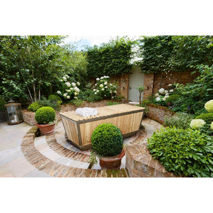 The Polar Plunge Tub in a walled courtyard garden with the cedar roll-up cover closed and rolled towels on top