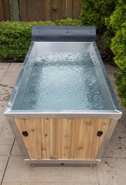 Front view of The Polar Plunge Tub filled with water, cedar roll-up cover pushed back