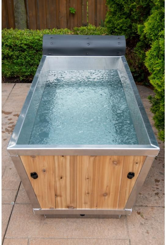Front view of The Polar Plunge Tub filled with water, cedar roll-up cover pushed back