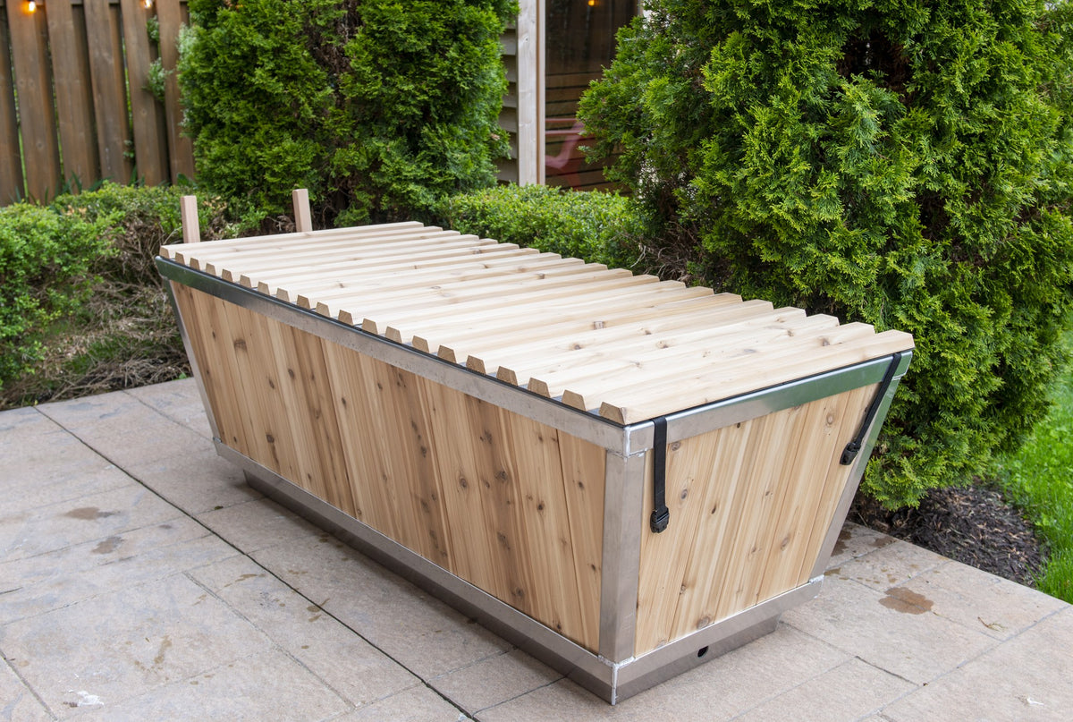 The Polar Plunge Tub in a garden with the cedar roll-up cover closed, seen from the corner