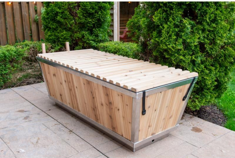 The Polar Plunge Tub in a garden with the cedar roll-up cover closed, seen from the corner