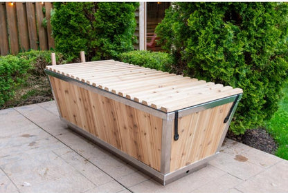 The Polar Plunge Tub in a garden with the cedar roll-up cover closed, seen from the corner