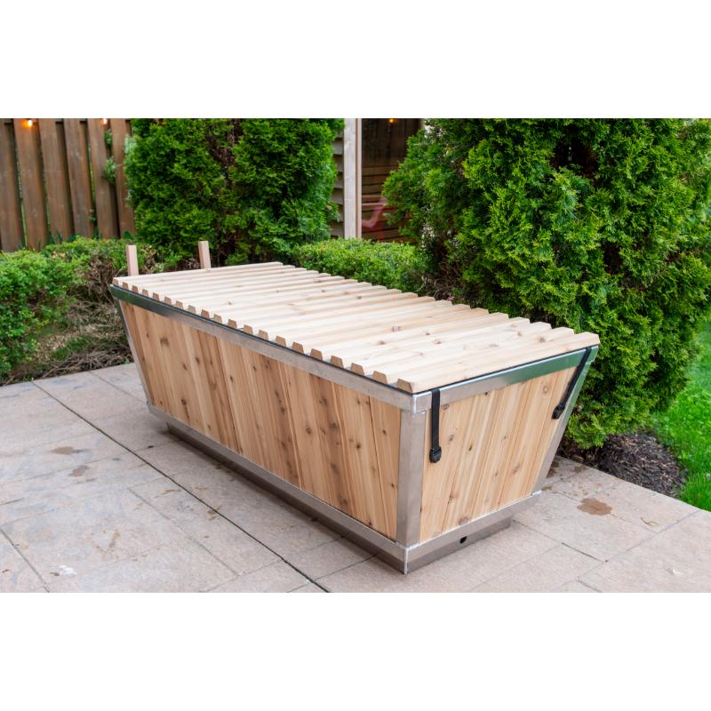 The Polar Plunge Tub in a garden with the cedar roll-up cover closed, seen from the corner