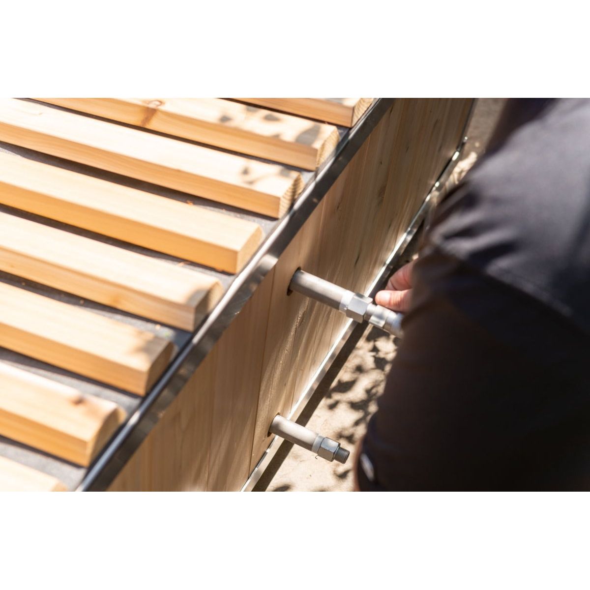 Close up of the knotty cedar roll-up cover slats on the stainless rim of The Polar Plunge Tub