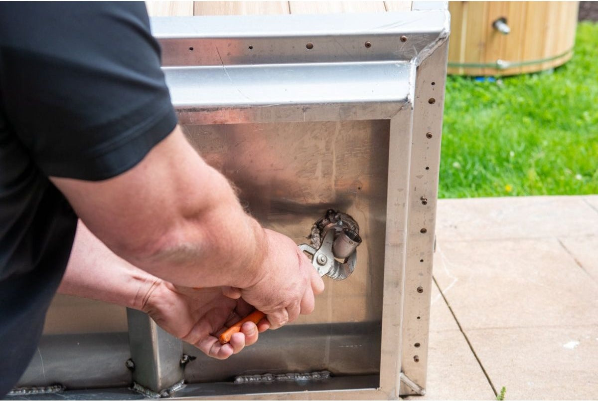 Tightening the drain elbow with a wrench inside the end frame of The Polar Plunge Tub