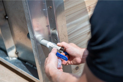 Threading a fitting onto the blue-handled ball valve at the end wall of The Polar Plunge Tub