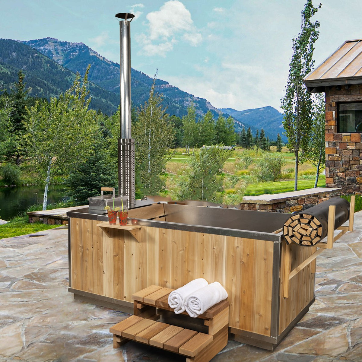 The Starlight Wood Burning Hot Tub on a flagstone patio below mountains, chimney at the stove end, shown with the optional aluminum interior and roll-up cover.