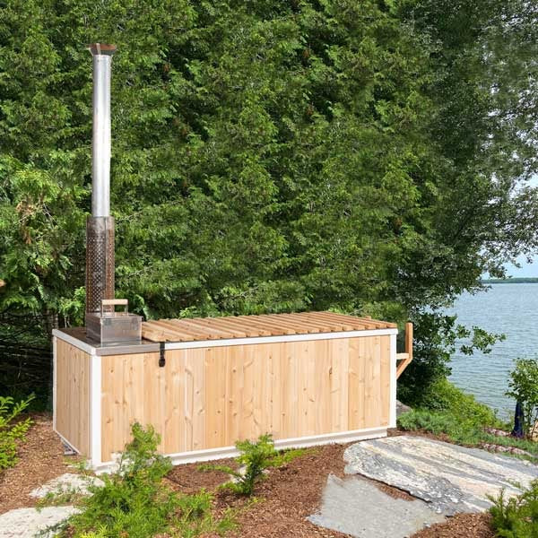 The Starlight beside a lake with the optional cedar cover rolled out over the water, chimney standing at the open stove end.
